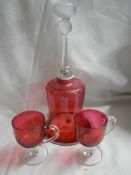 A Cranberry glass bell and two cranberry glass footed cups.