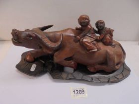 An Asian wooden buffaloo with two boys on its back.