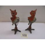 A pair of Austrian Devil candlesticks (one horn on each devil is missing or damaged).