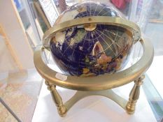 A gem stone terrestrial globe on a brass stand.