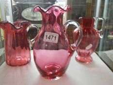 Three mid 20th century cranberry glass jugs.
