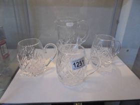 A good quality cut glass jug and three cut glass tankards.