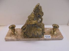 A brass figure with candleholders on a marble base.
