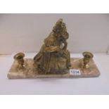 A brass figure with candleholders on a marble base.