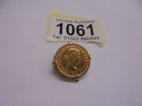 A gold coloured sixpence in an a/f mount.