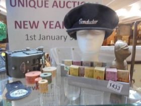 A vintage bus punch ticket machine, tickets and a conductor's hat.