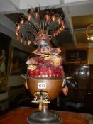 A copper samovar adorned with a grotesque doll.