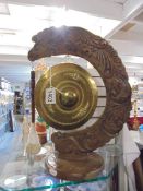 An Asian brass gong on carved stand.