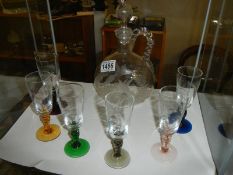 An Engraved decanter with six engraved glasses on coloured glass stems.