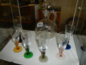 An Engraved decanter with six engraved glasses on coloured glass stems.