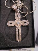 A white stone set cross in silver on a white metal chain.