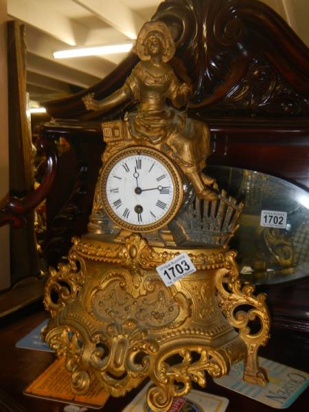 A gilded mantel clock surmounted figure.