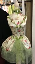 A Mannequin with green netting and a satin style flower bodice and embellishments