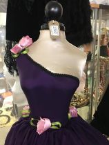 A Mannequin dressed in purple with pink flowers and black stand