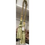 A pair of green and gold curtain tie backs with tassels