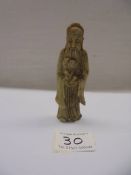 A sandstone oriental figure holding a child, 11 cm.