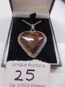 An amber heart set in a silver mount with attached silver chain.