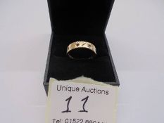 A textured and worked 9ct gold band ring set with garnets and clear stones, circa 1970/80's, size O