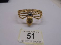 A yellow metal bangle fashioned as a spider,.