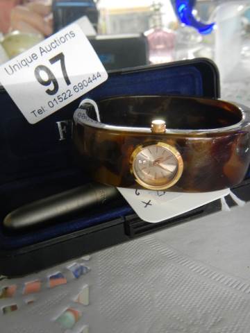 A bangle watch and a cased pen.