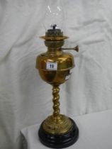 A brass oil lamp on a pot base and complete with chimney.