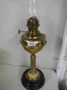 A brass oil lamp with reeded column on a pot base complete with chimney.