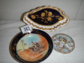 Three porcelain dishes including one with desert scene.