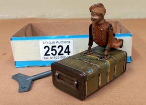 A German Gescha clockwork express boy & on a suitcase, working with key