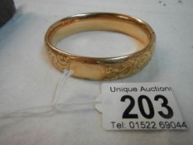 An engraved gold coloured bangle.