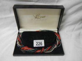 A boxed multi coloured necklace.