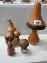 A carved mouse sitting on a mushroom and other wooden mushrooms.