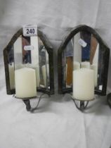 A pair of wall mounting candle holders with mirrors in back.