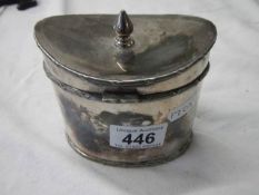 A silver plate tea caddy in the shape of a Victorian hat box.