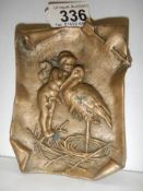 A bronze wall plaque featuring a stork with an angel, 12 x 9 cm.