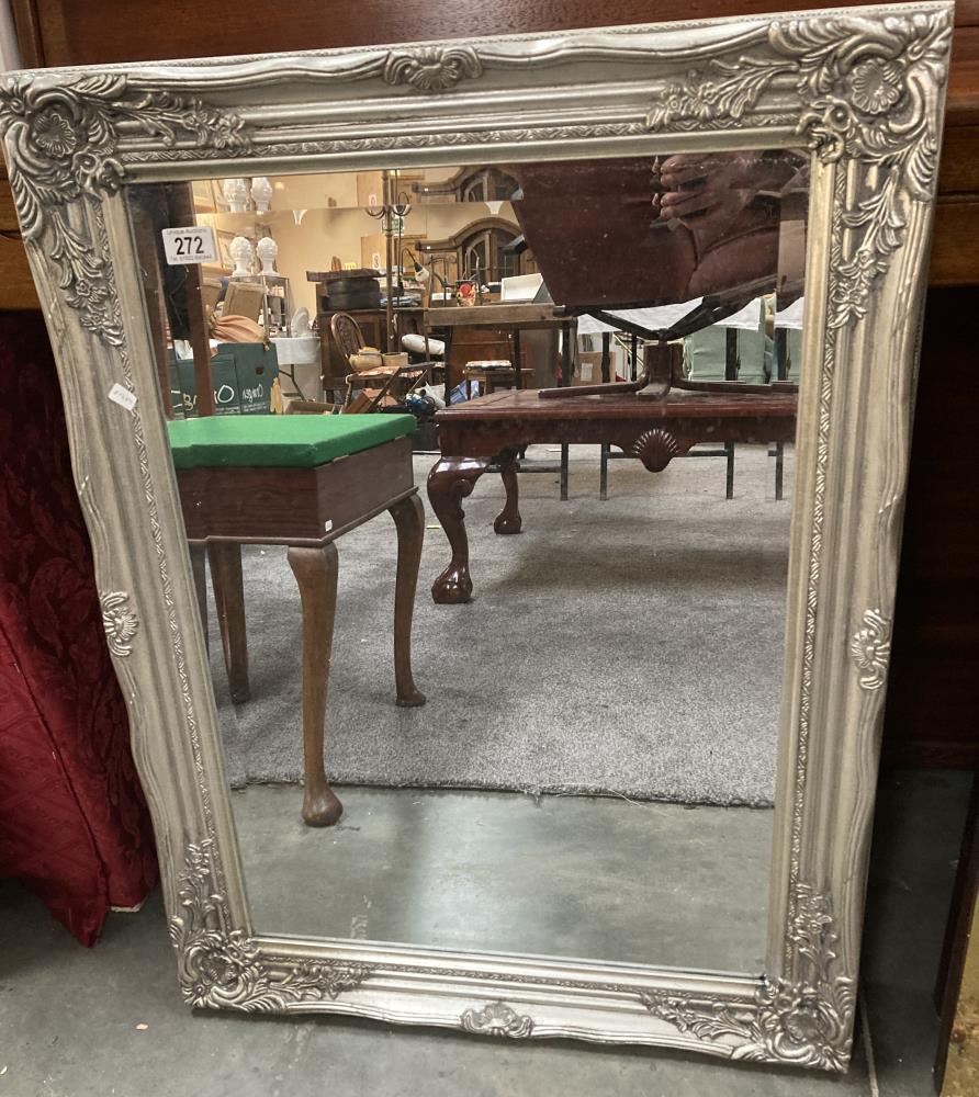 An ornate silver coloured bevelled mirror 64 x 84cm