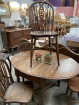 An oval drop leaf table with 4 wheel back chairs