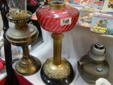 Two oil lamp bases and a brass oil lamp font, (cranberry glass font cracked).