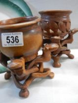 Two wooden pots on wooden stands.