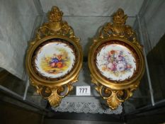 A pair of gilt framed ceramic wall plaques.