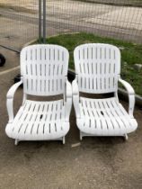 A pair of white garden loungers