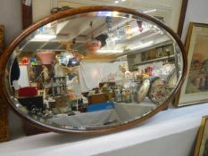 An oak framed oval bevel edged mirror in excellent condition,. COLLECT ONLY.