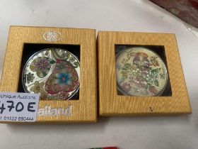 Two boxed powder compacts.
