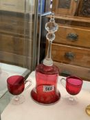 A Cranberry glass bell and two cranberry glass footed cups.