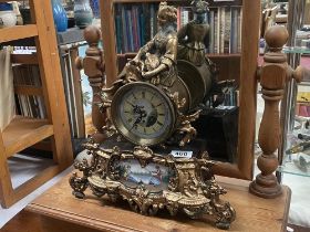 A French spelter mantel clock with hand painted panel with porcelain, panel and face filledwith