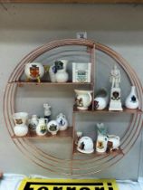 A quantity of crested ware on a copper coloured shelf includes Goss ware