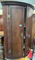 A bow fronted inlaid mahogany hanging corner cupboard with 3 interior shelves lock with key brass