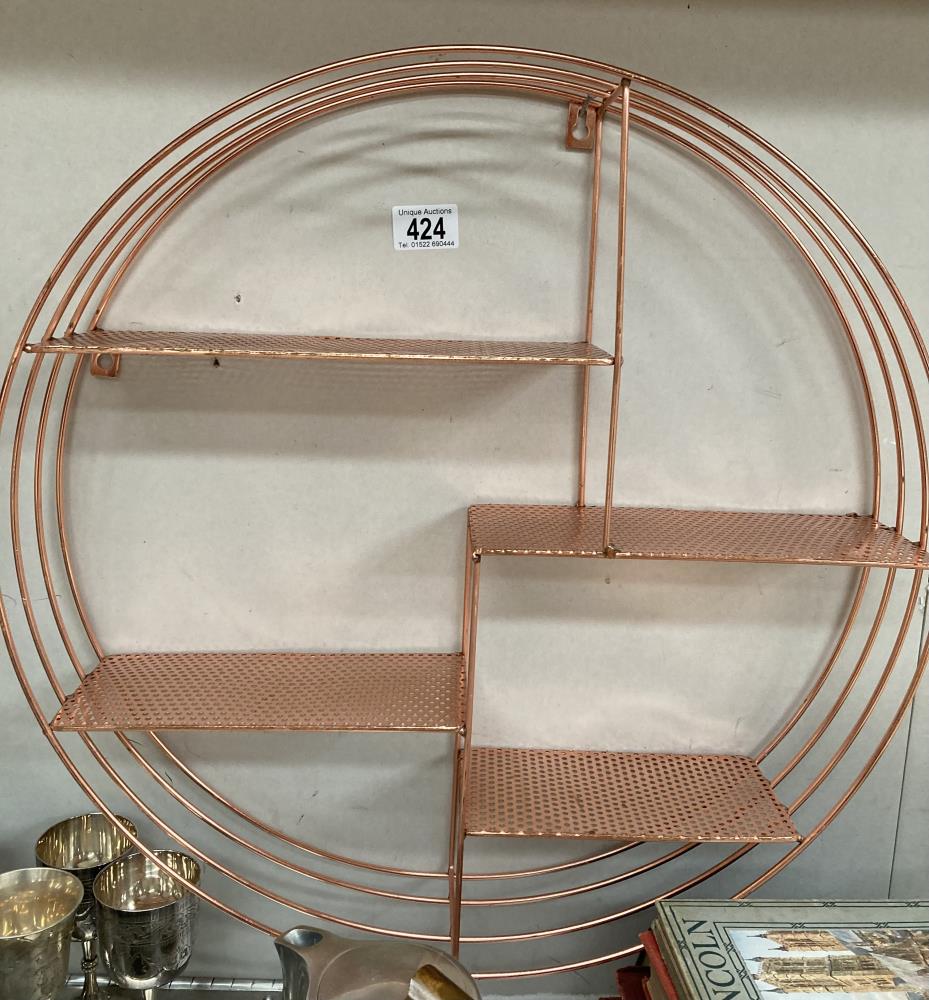 A circular copper coloured wall shelf unit