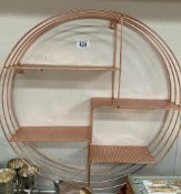 A circular copper coloured wall shelf unit