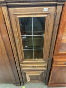A medium oak effect cupboard with glazed and leaded upper cupboard containing two glass shelves,
