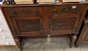 An Oak side board with decorative carving applied to draw and door fronts, trop pulls, turned